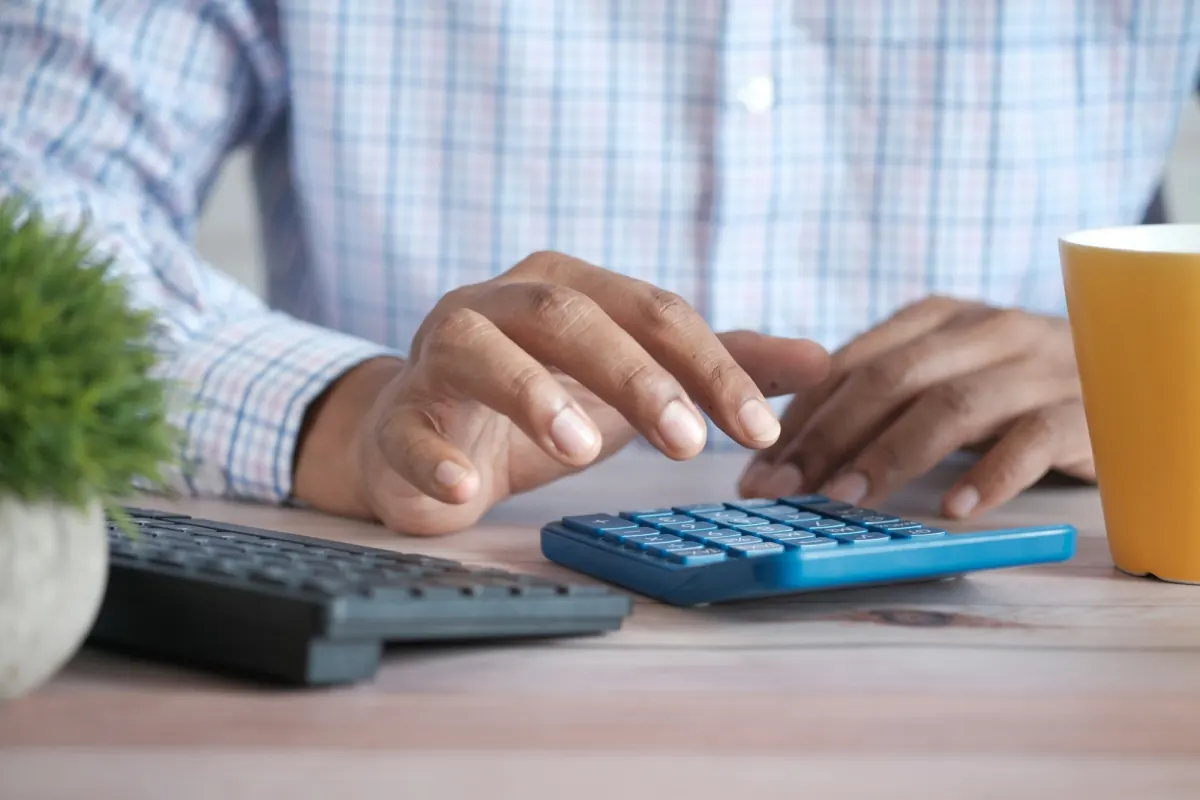 A man's hands working a calculator at a desk