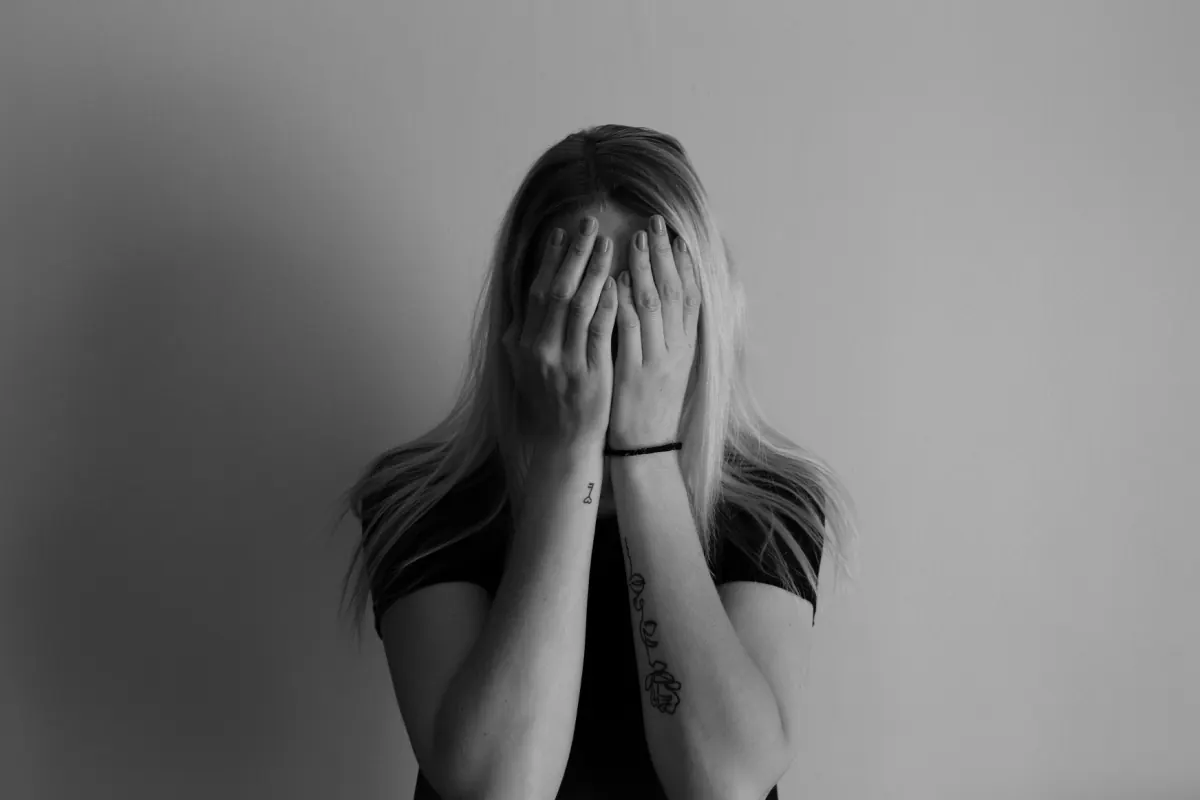 A woman covering her face with both hands, in black and white