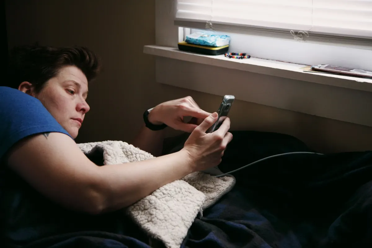 A person lying in bed, scrolling on their phone