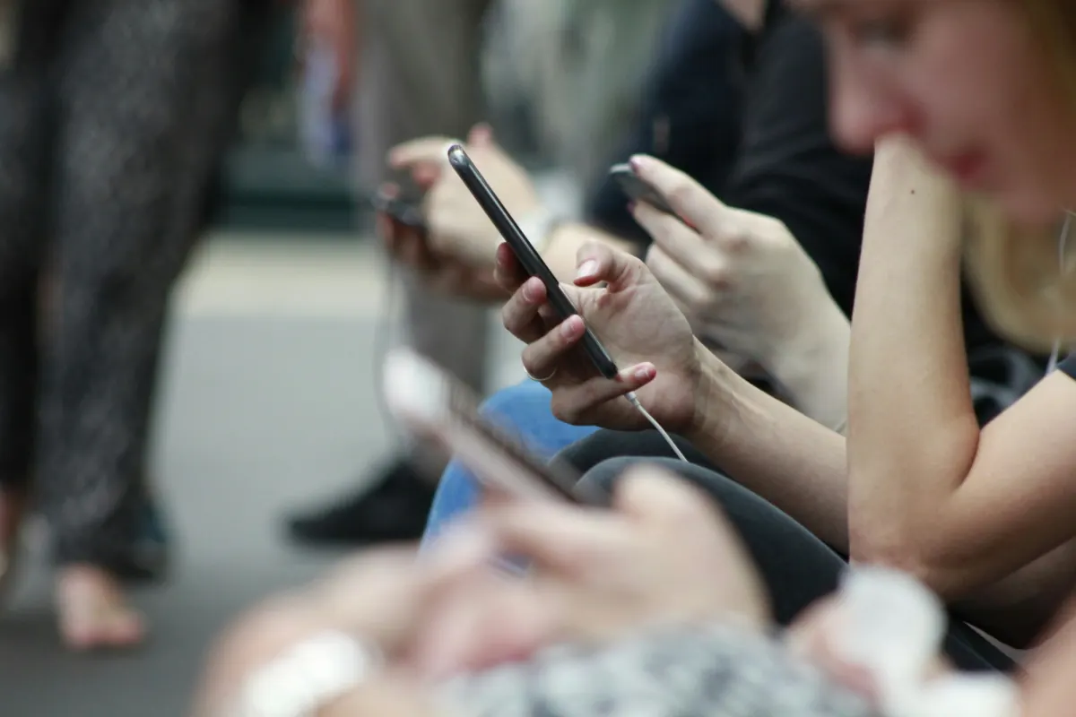 People sitting side by side, each looking at a smartphone