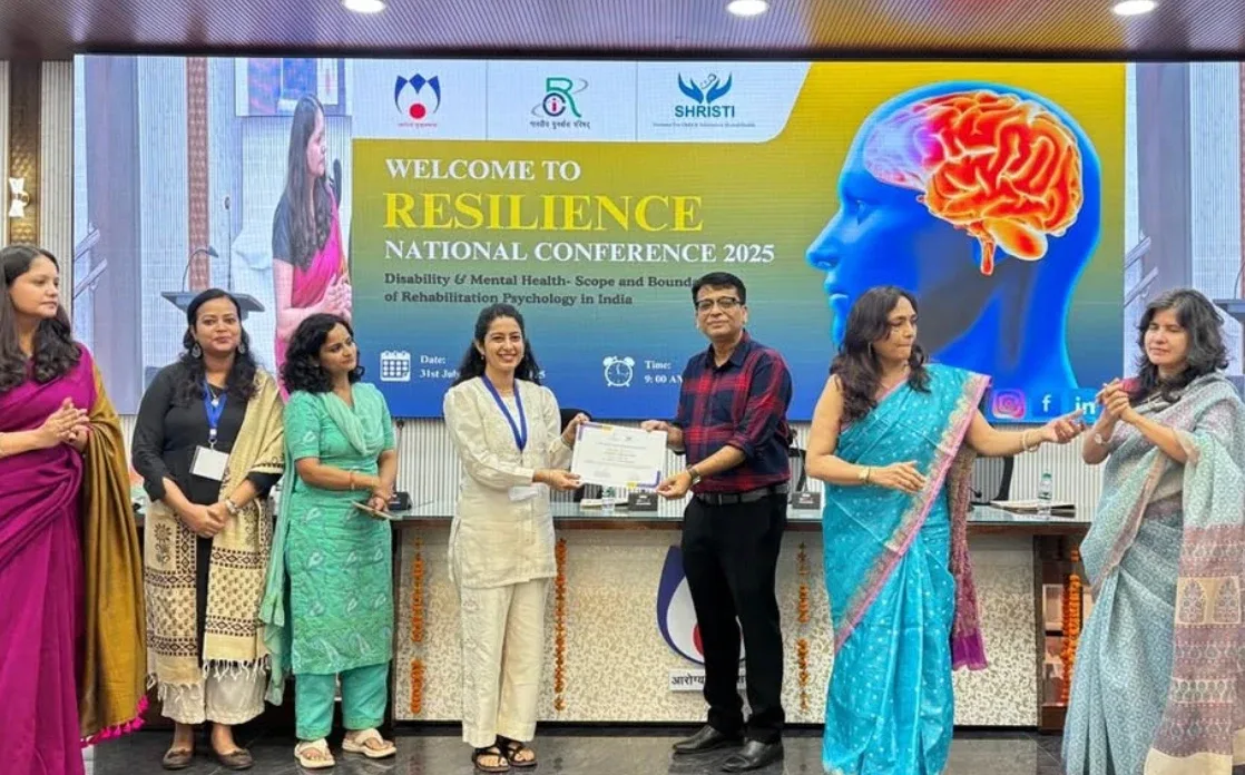 A certificate being presented on stage at RESILIENCE National Conference 2025, with Anamika Rawlani and fellow clinicians